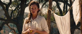 Movie still from “Saving Mr. Banks” (2013), directed by John Lee Hancock – A woman holding an apple while standing next to a tree; Medium shot, Over the shoulder angle