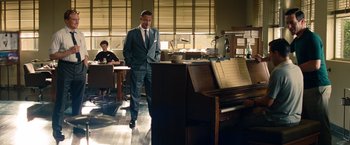 Movie still from “Saving Mr. Banks” (2013), directed by John Lee Hancock – A man in a suit standing in front of a piano; Wide shot, Over the shoulder angle