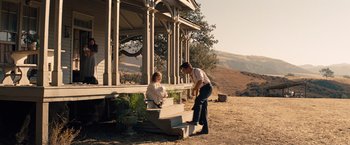 Movie still from “Saving Mr. Banks” (2013), directed by John Lee Hancock – A man and a woman sitting on steps near a house; Wide shot, Low angle