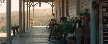 Movie still from “Saving Mr. Banks” (2013), directed by John Lee Hancock – A woman sitting on a rocking chair on the porch of a house; Extreme Wide shot, High angle