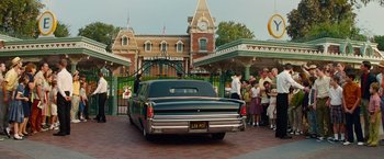Movie still from “Saving Mr. Banks” (2013), directed by John Lee Hancock – An old car parked in front of a building with people standing around it; Wide shot, Over the shoulder angle