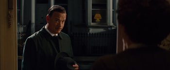 Movie still from “Saving Mr. Banks” (2013), directed by John Lee Hancock – A man wearing a suit and hat in a dark room; Close Up shot, Over the shoulder angle