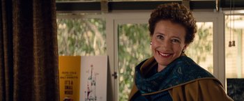 Movie still from “Saving Mr. Banks” (2013), directed by John Lee Hancock – A woman smiling for the camera in front of a window; Close Up shot, Over the shoulder angle
