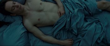 Movie still from “Shame” (2011), directed by Steve McQueen – A man laying on a bed with a blue blanket; Extreme Close Up shot, Overhead angle