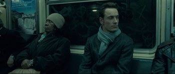Movie still from “Shame” (2011), directed by Steve McQueen – A man sitting on a bus next to another man; Medium shot, Low angle