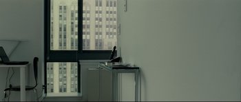 Movie still from “Shame” (2011), directed by Steve McQueen – A table that has a phone on it; Medium shot, Over the shoulder angle