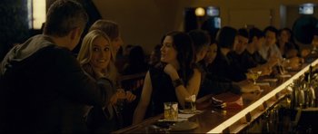 Movie still from “Shame” (2011), directed by Steve McQueen – A group of people sitting at a bar together; Medium shot, Over the shoulder angle