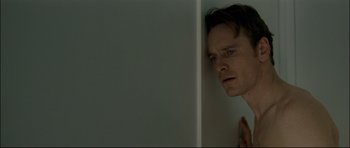 Movie still from “Shame” (2011), directed by Steve McQueen – A man leaning up against a wall with his hands on his face; Close Up shot, Low angle