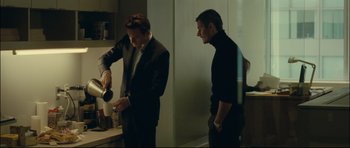 Movie still from “Shame” (2011), directed by Steve McQueen – Two men in a kitchen one of them is pouring a cup of coffee; Medium shot, Over the shoulder angle
