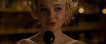 Movie still from “Shame” (2011), directed by Steve McQueen – A woman with blonde curly hair is holding a microphone; Close Up shot, Low angle
