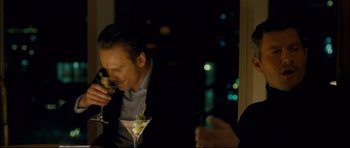 Movie still from “Shame” (2011), directed by Steve McQueen – A man sitting at a table with a glass of wine; Medium shot, Over the shoulder angle