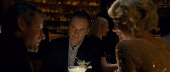 Movie still from “Shame” (2011), directed by Steve McQueen – A man sitting at a table with a drink in front of him; Close Up shot, Over the shoulder angle