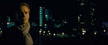 Movie still from “Shame” (2011), directed by Steve McQueen – A man standing in front of a city skyline at night; Close Up shot, Over the shoulder angle