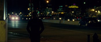 Movie still from “Shame” (2011), directed by Steve McQueen – A person standing on the side of a road at night; Wide shot, Over the shoulder angle