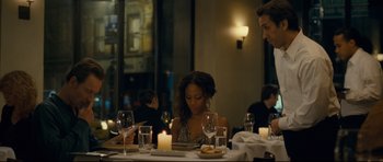 Movie still from “Shame” (2011), directed by Steve McQueen – A woman sitting at a dinner table looking at a tablet; Medium shot, Over the shoulder angle