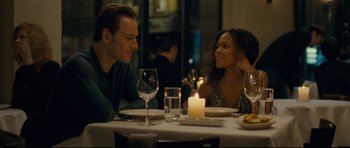 Movie still from “Shame” (2011), directed by Steve McQueen – A man and a woman sitting at a dinner table; Medium shot, Over the shoulder angle