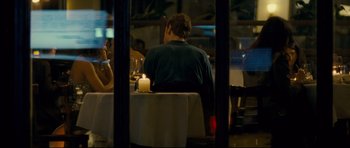 Movie still from “Shame” (2011), directed by Steve McQueen – A man sitting at a table with a candle in front of a woman; Medium shot, Over the shoulder angle