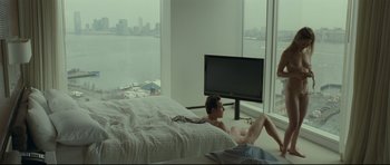 Movie still from “Shame” (2011), directed by Steve McQueen – A man laying on a bed in front of a tv; Wide shot, High angle