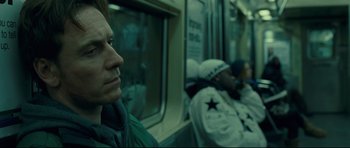 Movie still from “Shame” (2011), directed by Steve McQueen – A man sitting on a train next to another man; Close Up shot, Over the shoulder angle