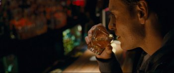 Movie still from “Shame” (2011), directed by Steve McQueen – A man drinking a glass of whiskey at a bar; Close Up shot, Over the shoulder angle