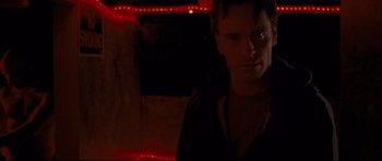 Movie still from “Shame” (2011), directed by Steve McQueen – A man standing in a dark room with lights behind him; Close Up shot, Low angle