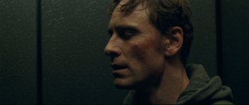 Movie still from “Shame” (2011), directed by Steve McQueen – A person wearing a jacket looking to the side; Close Up shot, Low angle
