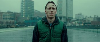 Movie still from “Shame” (2011), directed by Steve McQueen – A man in a green jacket standing in the street; Medium shot, Over the shoulder angle