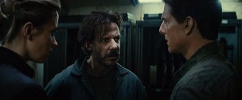 Movie still from “Edge of Tomorrow” (2014), directed by Doug Liman – A man with a beard talking to another man in a room; Close Up shot, Over the shoulder angle