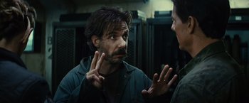 Movie still from “Edge of Tomorrow” (2014), directed by Doug Liman – A man talking to another man while holding his hands up; Close Up shot, Over the shoulder angle