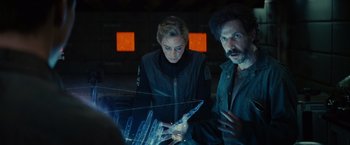 Movie still from “Edge of Tomorrow” (2014), directed by Doug Liman – A man and a woman are looking at something on a table; Medium shot, Over the shoulder angle