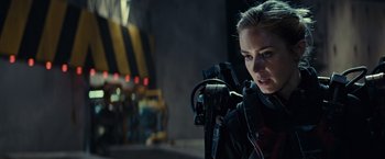 Movie still from “Edge of Tomorrow” (2014), directed by Doug Liman – A woman holding a camera in front of a building; Close Up shot, Over the shoulder angle