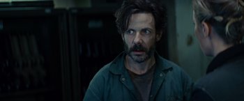 Movie still from “Edge of Tomorrow” (2014), directed by Doug Liman – A man with long hair and a beard stares at the camera; Close Up shot, Over the shoulder angle