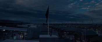 Movie still from “Edge of Tomorrow” (2014), directed by Doug Liman – A man standing on top of a building next to an american flag; Extreme Wide shot, Low angle