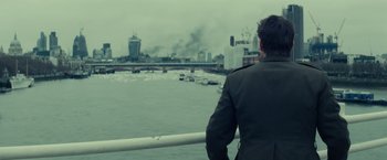 Movie still from “Edge of Tomorrow” (2014), directed by Doug Liman – A man standing on a bridge looking at a city; Medium shot, Over the shoulder angle
