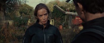 Movie still from “Edge of Tomorrow” (2014), directed by Doug Liman – A woman in black jacket standing next to a tree branch; Close Up shot, Over the shoulder angle