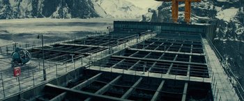 Movie still from “Edge of Tomorrow” (2014), directed by Doug Liman – An industrial area in the middle of a snowy mountain range; Extreme Wide shot, High angle