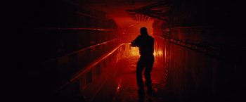 Movie still from “Edge of Tomorrow” (2014), directed by Doug Liman – A person in a dark room with a red light; Wide shot, Low angle