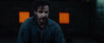 Movie still from “Edge of Tomorrow” (2014), directed by Doug Liman – A man with a beard is looking at the camera; Close Up shot, Over the shoulder angle