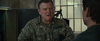 Movie still from “Edge of Tomorrow” (2014), directed by Doug Liman – An older man in a camouflage shirt is looking at the camera; Close Up shot, Over the shoulder angle