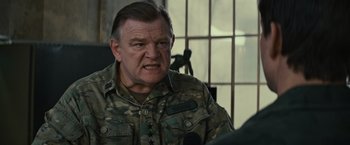 Movie still from “Edge of Tomorrow” (2014), directed by Doug Liman – An older man in a military uniform is looking at the camera; Close Up shot, Over the shoulder angle