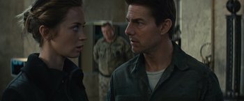 Movie still from “Edge of Tomorrow” (2014), directed by Doug Liman – A man and a woman are looking at each other in front of another man in fatigues; Close Up shot, Over the shoulder angle
