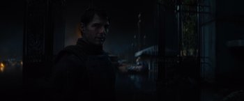 Movie still from “Edge of Tomorrow” (2014), directed by Doug Liman – A man standing in the dark in front of a building; Close Up shot, Over the shoulder angle