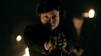 Movie still from “Sherlock” (2010), created by Steven Moffat – A woman in a black jacket is holding something in her hand; Close Up shot, Over the shoulder angle