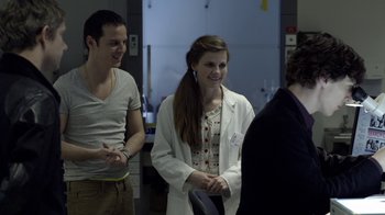 Movie still from “Sherlock” (2010), created by Steven Moffat – A group of people standing next to each other in a room; Medium shot, Over the shoulder angle