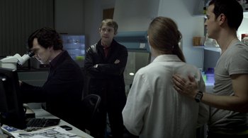 Movie still from “Sherlock” (2010), created by Steven Moffat – A man standing in front of two women in front of a mirror; Medium shot, Over the shoulder angle