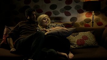 Movie still from “Sherlock” (2010), created by Steven Moffat – A man and a woman sitting on a couch watching tv; Medium shot, High angle