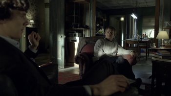 Movie still from “Sherlock” (2010), created by Steven Moffat – Two people sitting on a couch in a living room; Medium shot, Over the shoulder angle
