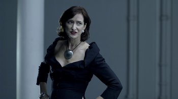 Movie still from “Sherlock” (2010), created by Steven Moffat – A woman in a black dress with a silver necklace; Medium shot, Over the shoulder angle
