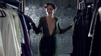 Movie still from “Sherlock” (2010), created by Steven Moffat – A woman in a green dress is holding a robe; Medium shot, Over the shoulder angle