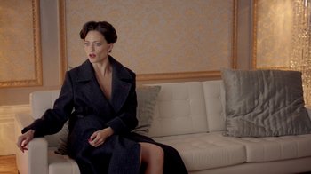 Movie still from “Sherlock” (2010), created by Steven Moffat – A woman sitting on top of a couch in a room; Medium shot, Over the shoulder angle